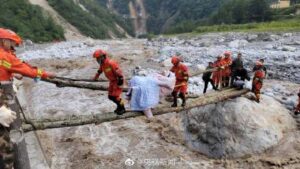 消防员背抬地震伤者踩木桥渡河