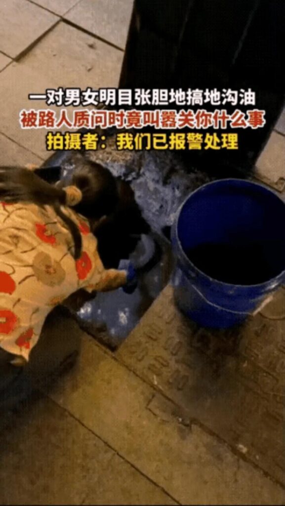 男女配合当街开井盖用勺挖地沟油